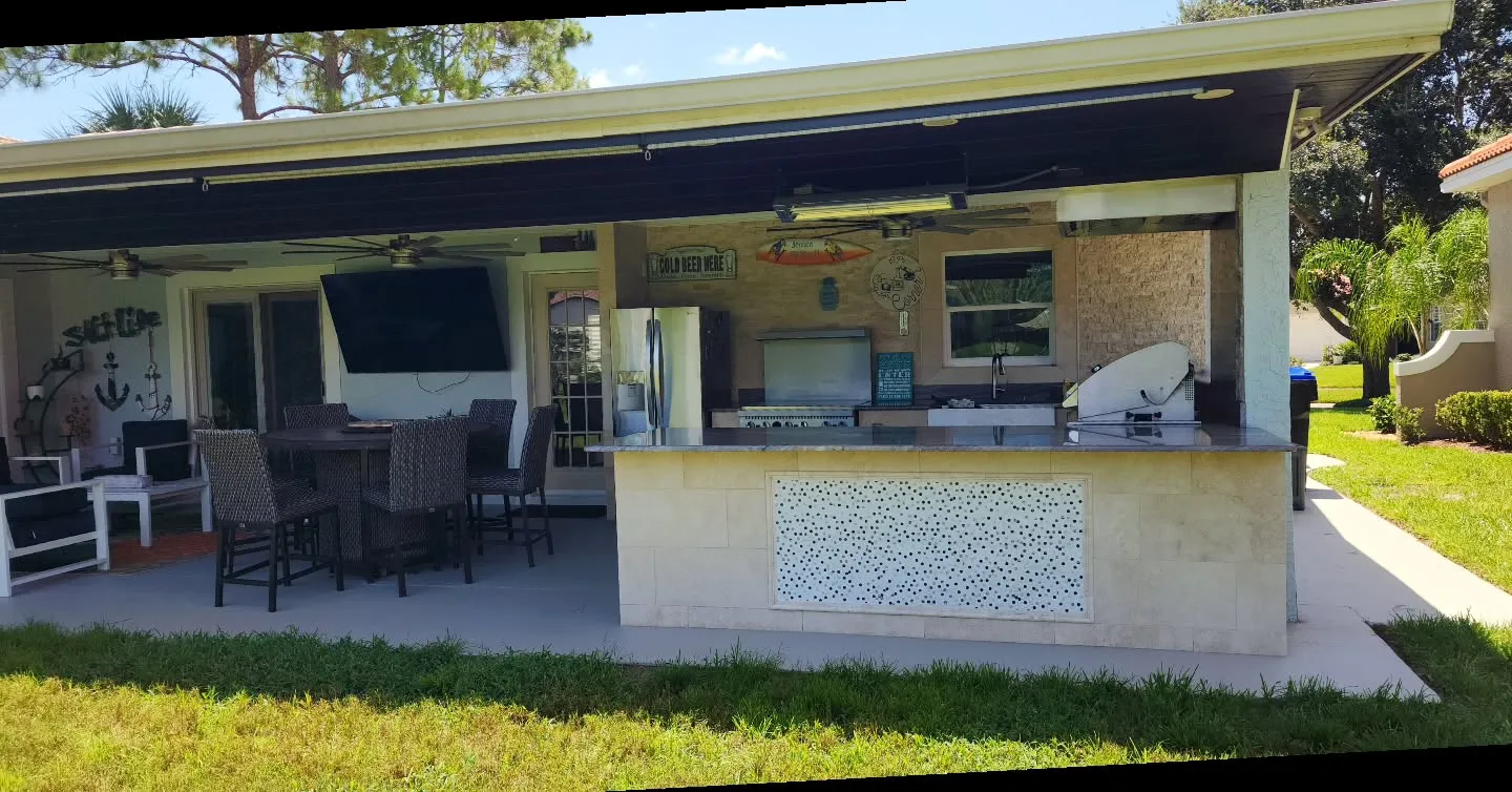 Covered outdoor kitchen with bar seating and stone tile
