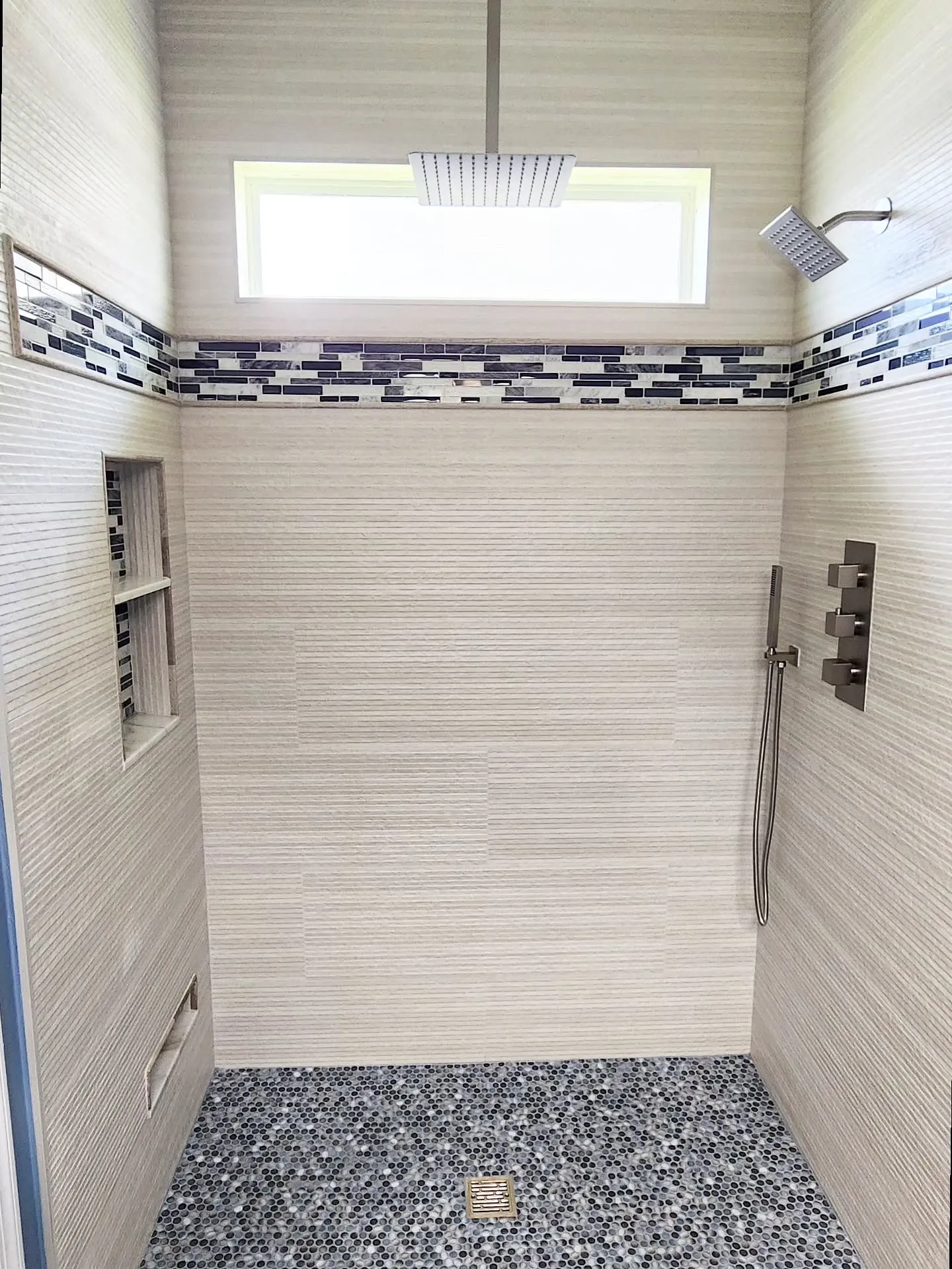 Curbless tile shower with mosaic accent band and pebble floor